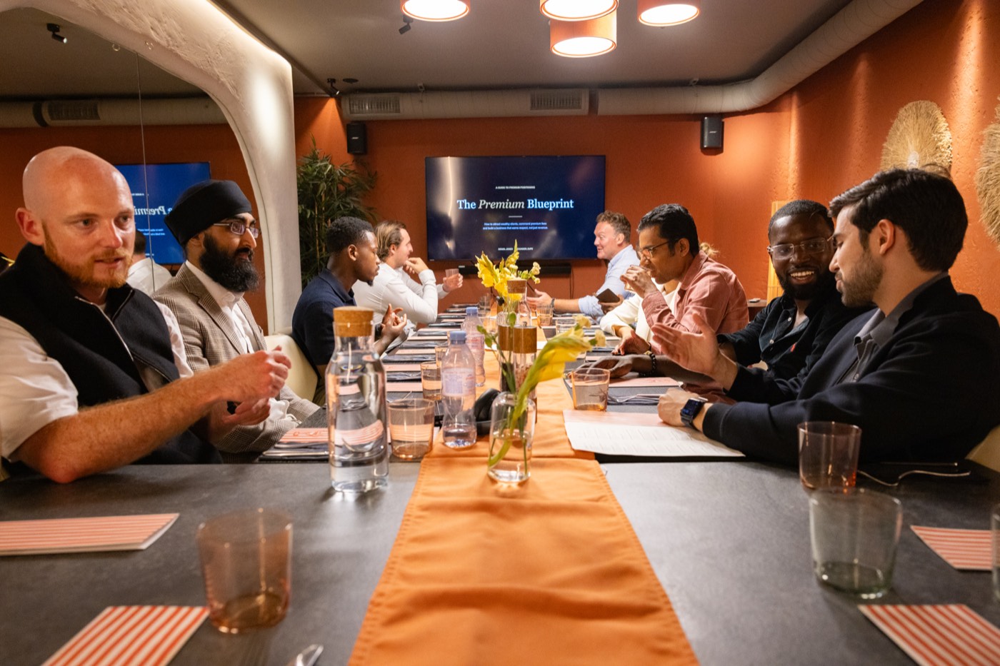 Founders listening at the table with The Premium Blueprint on screen