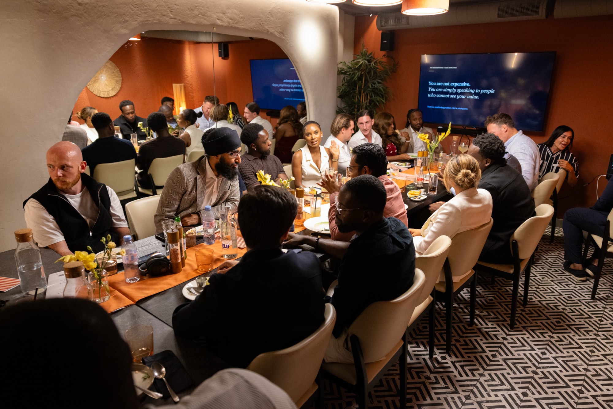 A long dinner table of founders in a warm private dining room